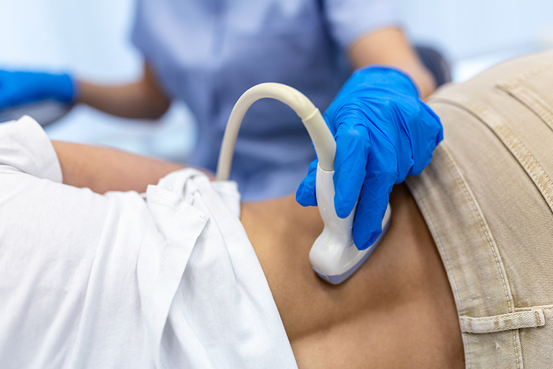 Closeup of woman's lower back as doctor does an ultrasound of her kidneys
