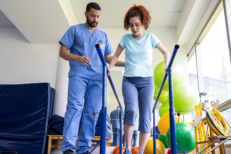 Young woman doing weight bearing exercise with physical therapist