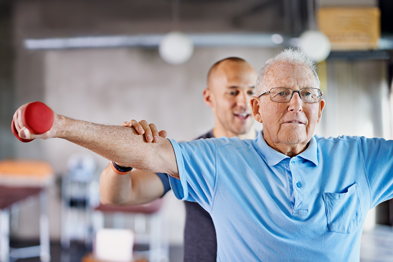 Senior man doing shoulder exercises with a physical therapist