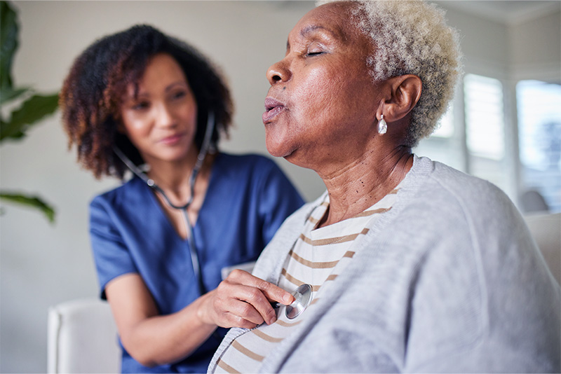 Doctor listening to senior patient's lungs with a stethoscope