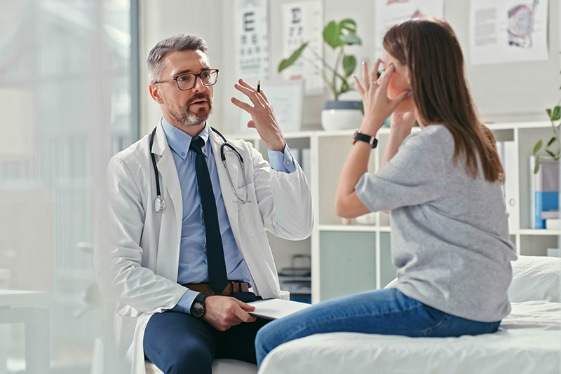 Patient describing symptoms to her doctor in an exam room
